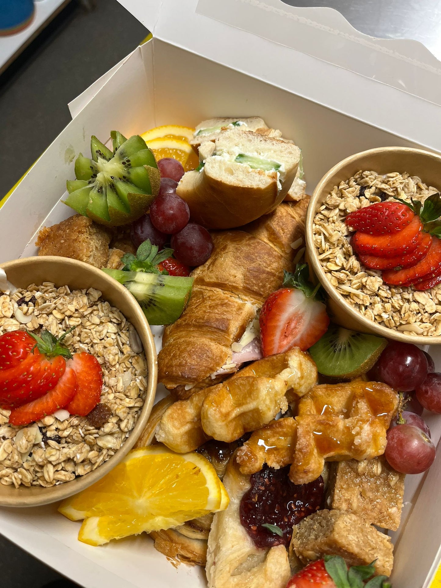 Assorted breakfast items including bowls of oatmeal, fruits, and pastries on a white plate.