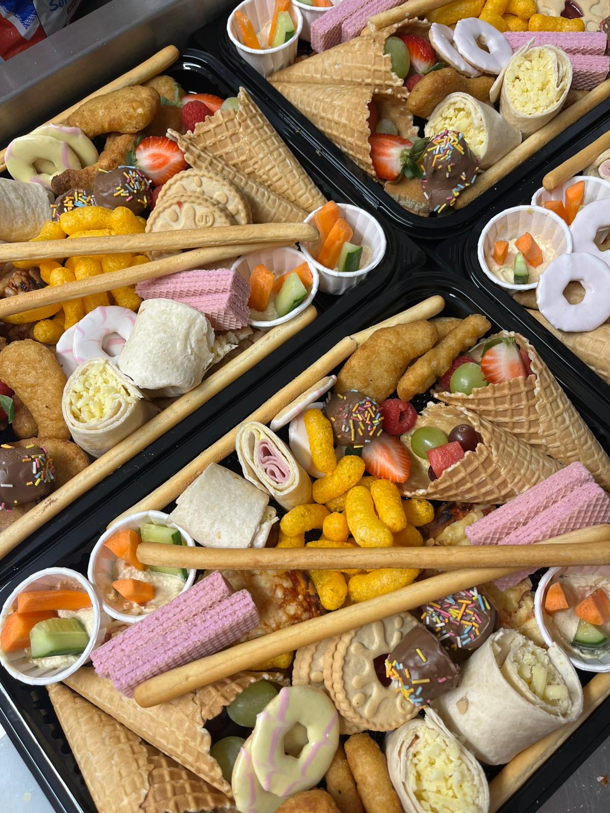 Assorted snacks including cookies, candies, and pastries in black trays.