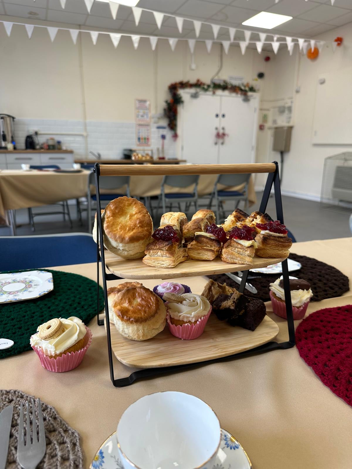 Three-tiered stand with pastries on a table in a room with chairs and tables.