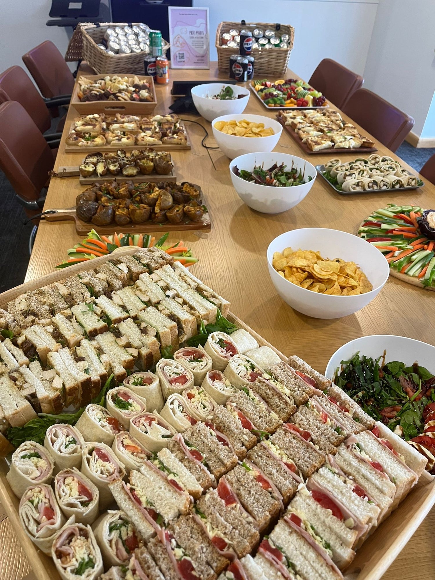 Table with various food items including sandwiches, salads, and snacks.